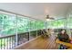 Relaxing screened porch with ceiling fan, wooden floor, and serene views of the surrounding lush greenery at 1460 Badingham Dr, Cumming, GA 30041