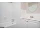 An elegant bathroom offers a bathtub with tile surround, modern sink and a sleek, round mirror at 1887 King Charles Sw Rd, Atlanta, GA 30331