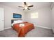 Cozy bedroom with plush gray carpet, ceiling fan, mounted TV, and a comfy bed with an orange quilt at 1887 King Charles Sw Rd, Atlanta, GA 30331