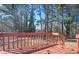Wooden deck with a red railing, pinecones on the deck, and forest in the background at 1887 King Charles Sw Rd, Atlanta, GA 30331