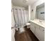 A bathroom has gray wood floors, a shower with a curtain, and white cabinets at 2706 Park Land Ln, Snellville, GA 30078