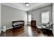 Bedroom with a hardwood floor, crib, dresser, chair, and light streaming through the windows at 828 Olmsted Ln, Duluth, GA 30097