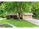 Charming home featuring lush landscaping, stone accents, and a large, shady tree in the front yard at 1075 Winding Branch Ln, Atlanta, GA 30338