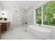 Bright bathroom with freestanding tub, glass shower, modern vanities, marble flooring and large window showcasing outdoor views at 1287 Star Ne Dr, Brookhaven, GA 30319
