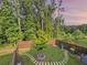 Backyard shot shows fenced yard with stone path, tree and beautiful border of mature trees at sunset at 150 Holden Way, Woodstock, GA 30189