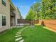 A fenced backyard featuring green grass, decorative stonework, and a beautiful border of trees at 150 Holden Way, Woodstock, GA 30189