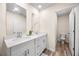 Bathroom featuring double sinks, white cabinetry, and modern fixtures; toilet in separate room at 2440 Rocky City Ln, Snellville, GA 30078