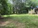 The back yard features the house and a spacious lawn, backed by lush, mature trees at 108 Fair Oaks Se Dr, Conyers, GA 30094