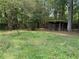 View of the backyard featuring an open storage shed, surrounded by trees and lush greenery at 108 Fair Oaks Se Dr, Conyers, GA 30094