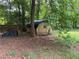 Backyard view of a partially covered wooden storage shed surrounded by lush greenery at 108 Fair Oaks Se Dr, Conyers, GA 30094