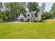 A white farmhouse style home with black trim sits on a sprawling green lawn surrounded by mature trees at 1870 Twin Branch Dr, Marietta, GA 30062