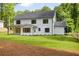 Backyard view of the modern farmhouse with black framed windows, a covered porch, and a spacious lawn at 1870 Twin Branch Dr, Marietta, GA 30062