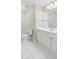 A well-lit bathroom features a white vanity with a large mirror and white tile floors and walls at 5882 Riverstone Cir # 15, Atlanta, GA 30339
