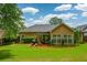 Backyard view of house showing patio with furniture set, grill, manicured lawn, and flower bed at 9013 Aldbury Dr, Locust Grove, GA 30248