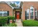 Charming home entrance with a red door, sidelight windows, decorative wreath, and manicured greenery at 9013 Aldbury Dr, Locust Grove, GA 30248