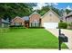 Well-kept home with a lush green lawn, colorful flower beds, brick accents, and a two-car garage at 9013 Aldbury Dr, Locust Grove, GA 30248