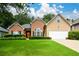 Charming home with a well-manicured lawn, brick accents, a two-car garage, and a welcoming red front door at 9013 Aldbury Dr, Locust Grove, GA 30248