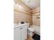 Tiled bathroom featuring white cabinets and toilet, a tub, and a decorative light fixture above the sink at 300 Rocky Cove Trl, Lawrenceville, GA 30044