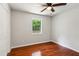 This bedroom features hardwood floors, a ceiling fan, and a window overlooking the lush greenery outside at 300 Rocky Cove Trl, Lawrenceville, GA 30044