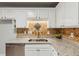Close-up of the kitchen featuring white cabinets, granite countertops, stainless steel sink, and decorative backsplash at 300 Rocky Cove Trl, Lawrenceville, GA 30044