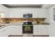 Well-lit kitchen featuring white cabinets, stainless steel appliances, granite countertops and decorative backsplash at 300 Rocky Cove Trl, Lawrenceville, GA 30044