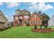 Stunning two-story brick home featuring manicured lawn and inviting front yard with beautiful garden and water feature at 1932 River Crest Way, Lawrenceville, GA 30045