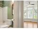 Bright bathroom featuring a tub, toilet, and a glimpse into a sunlit room with large windows at 242 12Th Ne St # 1A, Atlanta, GA 30309