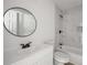 Bathroom with marble tile, black shower head and faucets, white vanity and round mirror at 6932 Eunice Dr, Riverdale, GA 30274