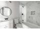 Bathroom with marble tile, black shower head and faucets, white vanity and round mirror at 6932 Eunice Dr, Riverdale, GA 30274