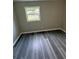 The bedroom features gray walls, grey wood-look flooring, and a window overlooking the property at 3730 Clovis Nw Ct, Atlanta, GA 30331