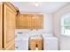 Bright laundry room features white washer and dryer units, storage cabinets, and a sink near a window at 2759 Bay Ridge Dr, Loganville, GA 30052