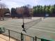 Exterior view of a well-maintained tennis court surrounded by trees and fencing at 505 Tilbury Dr, Suwanee, GA 30024