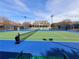 Exterior view of a well-maintained tennis court with lighting and residential building in the background at 505 Tilbury Dr, Suwanee, GA 30024