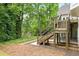 Backyard featuring a wooden staircase leading to a deck, lush landscaping, and a serene view of a pond at 12230 Asbury Park Dr, Roswell, GA 30075