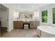 Luxurious bathroom featuring a modern vanity with double sinks and a soaking tub under a window at 12230 Asbury Park Dr, Roswell, GA 30075