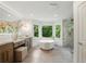 Luxurious bathroom featuring a freestanding tub, a glass-enclosed shower, and large windows overlooking the yard at 12230 Asbury Park Dr, Roswell, GA 30075