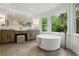 Elegant bathroom with a freestanding tub next to large windows with green views and a vanity area at 12230 Asbury Park Dr, Roswell, GA 30075