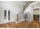Bright foyer featuring a staircase, hardwood floors, stylish mirror, and view into the kitchen at 12230 Asbury Park Dr, Roswell, GA 30075
