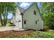 Side exterior featuring a two-car garage, white brick, landscaped yard, and pathway to the entrance at 12230 Asbury Park Dr, Roswell, GA 30075
