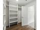 Bright walk-in closet with white shelving and hanging rods, offering ample storage solutions and hardwood flooring at 12230 Asbury Park Dr, Roswell, GA 30075