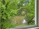 Scenic window view overlooking a tranquil pond surrounded by lush green trees and foliage at 12230 Asbury Park Dr, Roswell, GA 30075