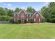 Beautiful two-story brick home with blue shutters and a well-manicured front yard with mature trees at 129 Crown Walk, Mcdonough, GA 30253
