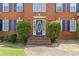 Close-up of a home's front entrance featuring a blue door, brick steps, and manicured greenery at 129 Crown Walk, Mcdonough, GA 30253