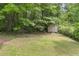 Backyard with a storage shed surrounded by mature trees, offering ample space at 129 Crown Walk, Mcdonough, GA 30253