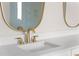 Close-up of bathroom vanity with white countertops, gold faucet, and oval mirrors at 3735 Tamiami Trl, Cumming, GA 30041