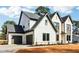Angle shot of a modern two-story home with light brick, dark trim, garage, and manicured landscaping at 3735 Tamiami Trl, Cumming, GA 30041
