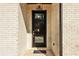 Close up view of a front door with a black frame and transom, with a black brick surround at 3735 Tamiami Trl, Cumming, GA 30041