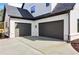 Attached two-car garage with dark doors and a concrete driveway, accented by manicured landscaping at 3735 Tamiami Trl, Cumming, GA 30041