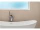 Close-up of a modern soaking tub with chrome hardware and neutral tile background at 3735 Tamiami Trl, Cumming, GA 30041