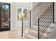 Modern staircase with light wood steps, black metal railings, and a view to the front door at 3735 Tamiami Trl, Cumming, GA 30041